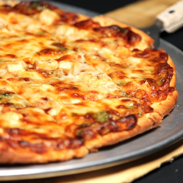 Close-up of a Romano's Chicago Pizzeria pizza with melted cheese and toppings on a metal pan.