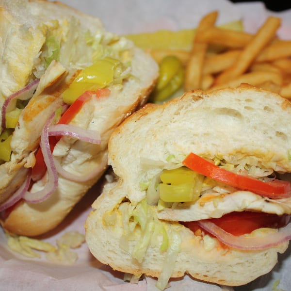 A Romano's Italian sub sandwich with chicken, lettuce, onions, and peppers, served with fries.